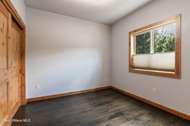 spare room featuring dark wood-type flooring and baseboards