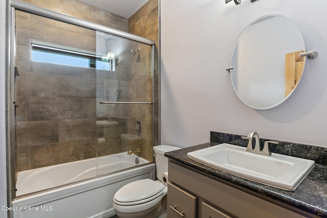 bathroom featuring vanity, combined bath / shower with glass door, and toilet