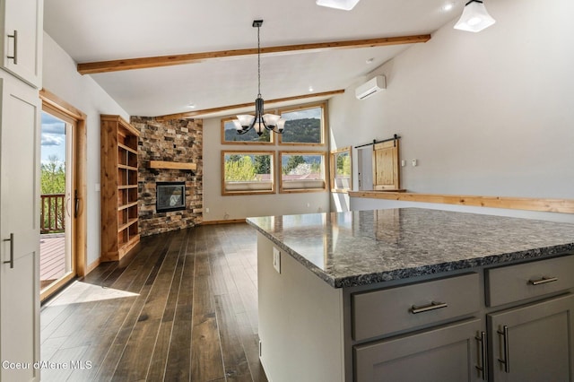 kitchen with an inviting chandelier, dark wood-style flooring, dark stone counters, a wall unit AC, and gray cabinetry