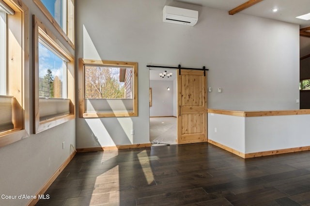 spare room featuring baseboards, a towering ceiling, a wall unit AC, and hardwood / wood-style floors