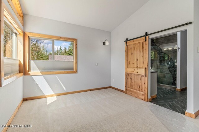 spare room with baseboards, a barn door, and carpet