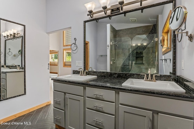 full bathroom with a sink, a shower stall, and double vanity