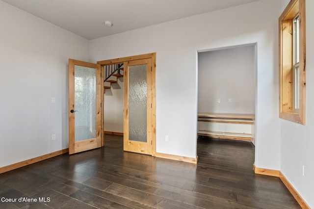 unfurnished room with baseboards, french doors, and wood finished floors