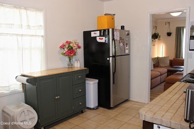 kitchen with freestanding refrigerator, tile countertops, and light tile patterned floors