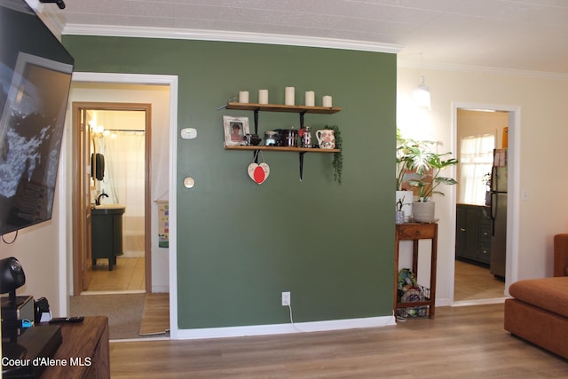 corridor with ornamental molding, baseboards, and wood finished floors