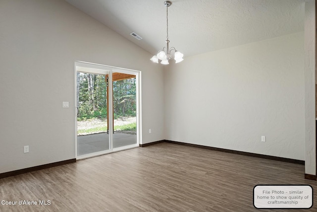 unfurnished room with an inviting chandelier, lofted ceiling, wood finished floors, and visible vents