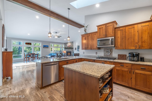 5867 W Sparrowhawk Dr, Rathdrum, ID 83858 - kitchen with stainless steel appliances, a sink, lofted ceiling with skylight, a peninsula, and brown cabinetry