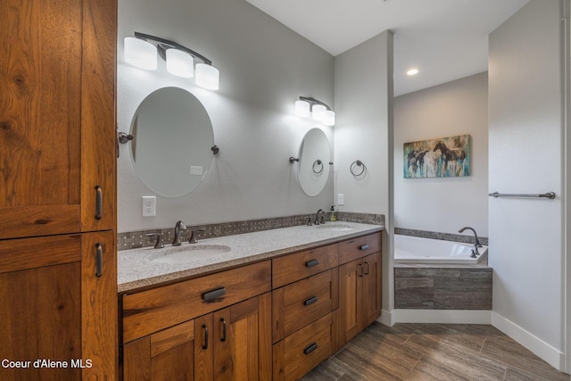 5867 W Sparrowhawk Dr, Rathdrum, ID 83858 - full bath with wood finished floors, double vanity, a sink, a bath, and baseboards