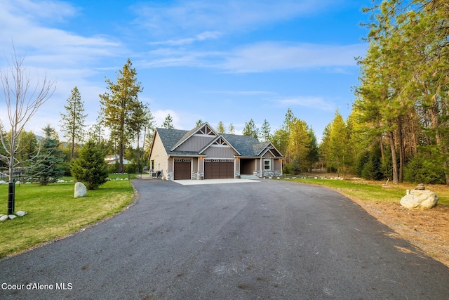 5867 W Sparrowhawk Dr, Rathdrum, ID 83858 - view of front of house featuring aphalt driveway, a front lawn, board and batten siding, stone siding, and a garage