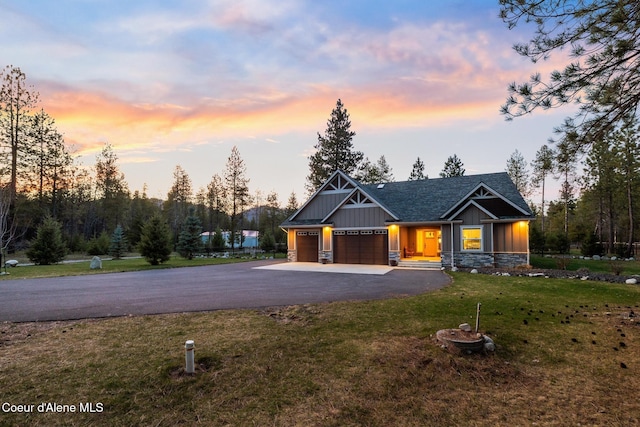 5867 W Sparrowhawk Dr, Rathdrum, ID 83858 - view of front of property featuring driveway, stone siding, an attached garage, board and batten siding, and a yard