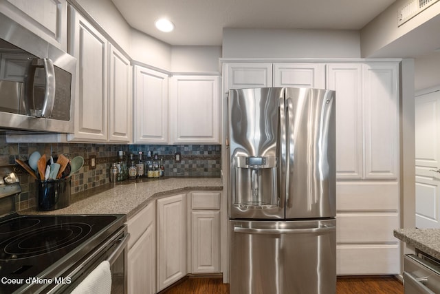 4549 S Arrow Point Dr # 207, Harrison, ID 83833 - kitchen with dark wood-style floors, stainless steel appliances, light stone countertops, tasteful backsplash, and white cabinetry