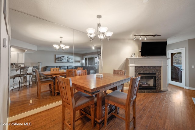 4549 S Arrow Point Dr # 207, Harrison, ID 83833 - dining room with a fireplace with flush hearth, track lighting, wood-type flooring, baseboards, and a notable chandelier