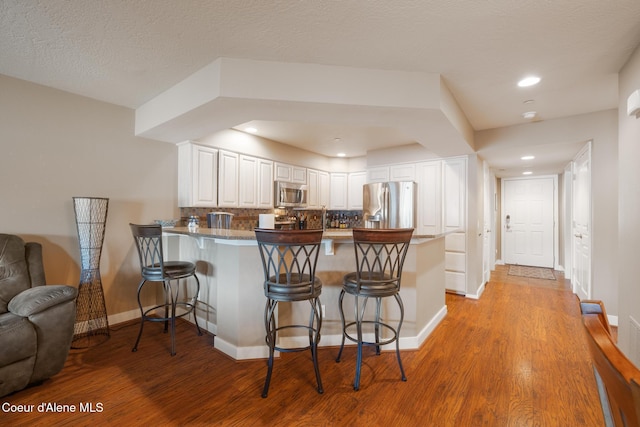 4549 S Arrow Point Dr # 207, Harrison, ID 83833 - kitchen with a kitchen breakfast bar, backsplash, baseboards, a peninsula, and appliances with stainless steel finishes