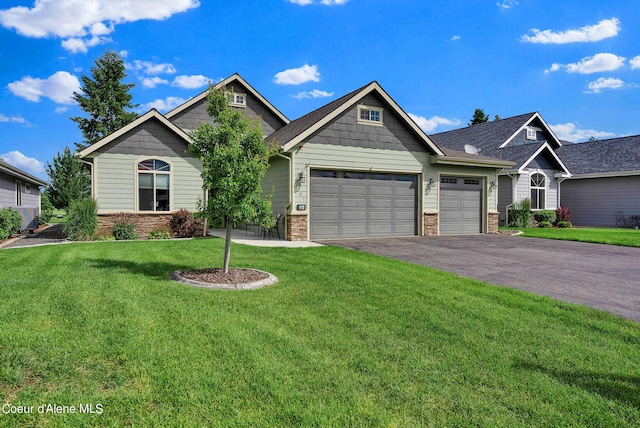 craftsman-style home featuring an attached garage, a front lawn, aphalt driveway, and stone siding