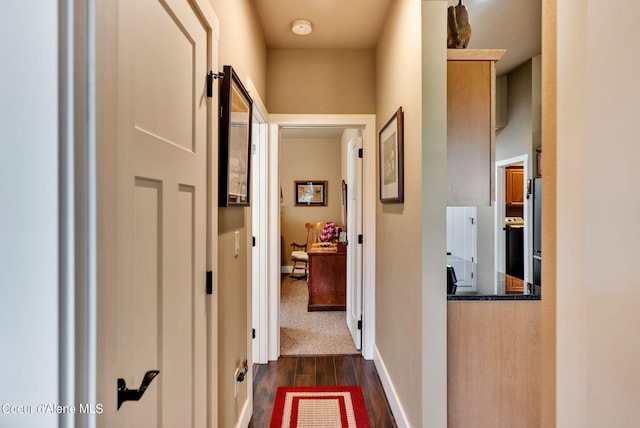 corridor featuring baseboards and dark wood-style floors