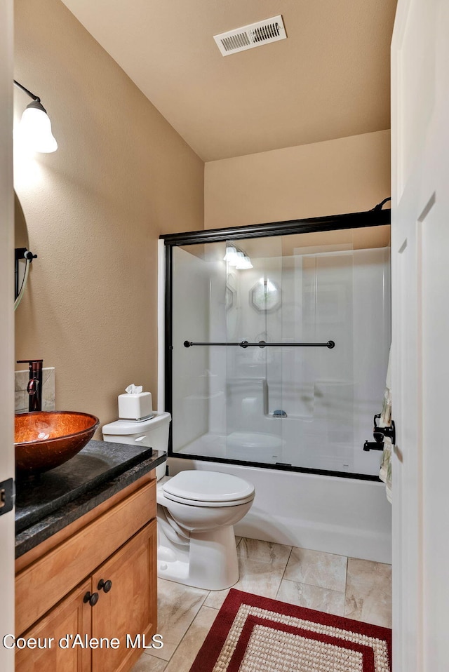 bathroom featuring shower / bath combination with glass door, toilet, vanity, and visible vents