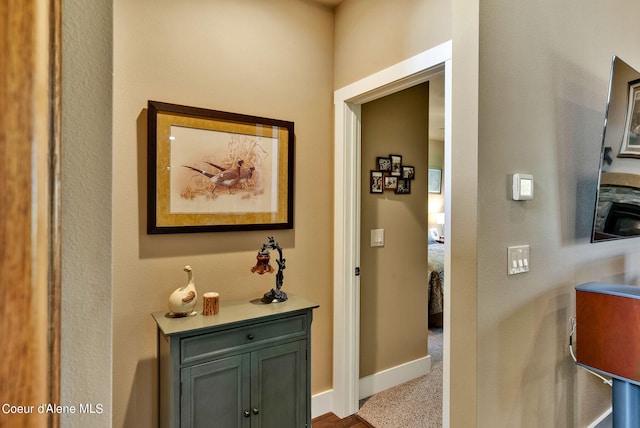 corridor with baseboards and carpet flooring