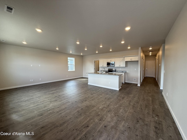 5147 E Norma Ave, Post Falls, ID 83854 - kitchen featuring stainless steel appliances, white cabinets, open floor plan, an island with sink, and dark wood-style floors