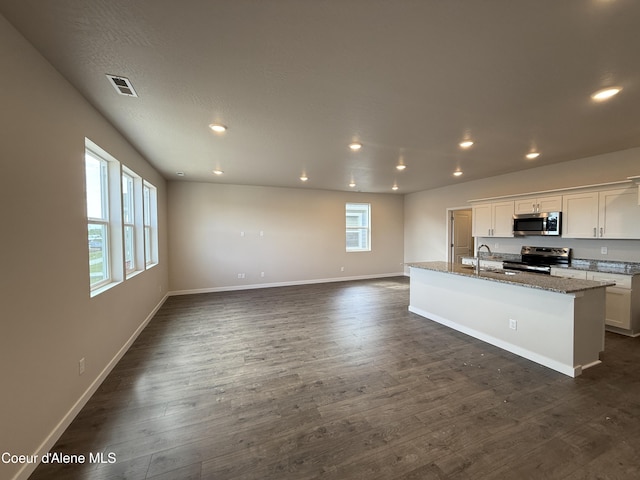 5147 E Norma Ave, Post Falls, ID 83854 - kitchen with stainless steel appliances, dark wood-style floors, recessed lighting, a center island with sink, and light stone counters