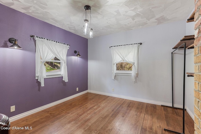 spare room with baseboards and hardwood / wood-style flooring