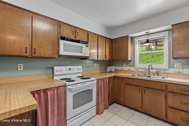 kitchen featuring a sink, white appliances, light countertops, decorative light fixtures, and light tile patterned floors