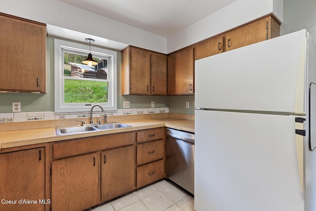 kitchen with stainless steel dishwasher, a sink, light countertops, and freestanding refrigerator