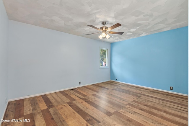 empty room featuring hardwood / wood-style flooring, baseboards, and a ceiling fan