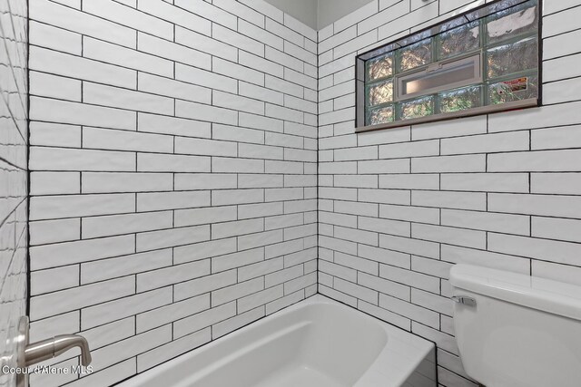 bathroom featuring washtub / shower combination and toilet
