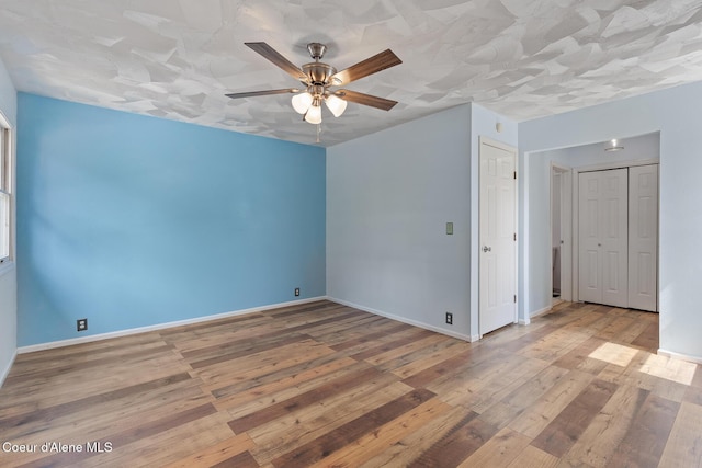 empty room with baseboards, a ceiling fan, and hardwood / wood-style floors