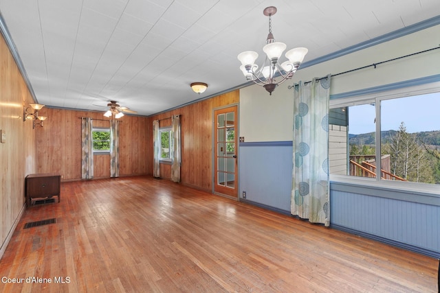 interior space with ceiling fan with notable chandelier, visible vents, wood-type flooring, wood walls, and a mountain view