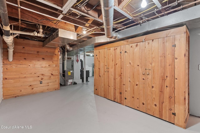 unfinished basement with heating unit and wood walls