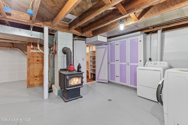 unfinished basement with stairway, a wood stove, and washer and clothes dryer