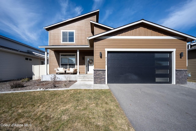 4302 N Donovan Ln, Post Falls, ID 83854 - modern home with a porch, asphalt driveway, a garage, stone siding, and a front lawn