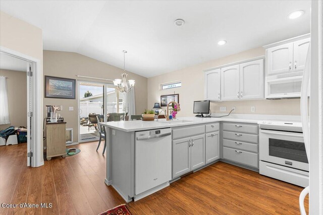 8514 W Grand Teton St, Rathdrum, ID 83858 - kitchen with a peninsula, a sink, a chandelier, lofted ceiling, and white appliances