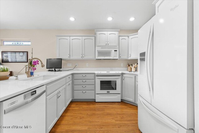 8514 W Grand Teton St, Rathdrum, ID 83858 - kitchen with a sink, recessed lighting, light wood-style floors, white appliances, and light countertops