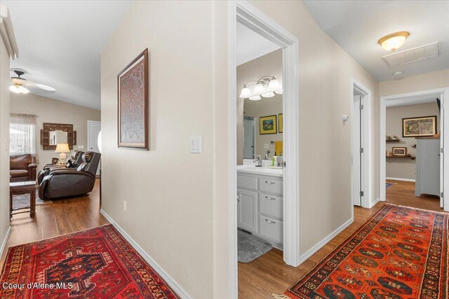 8514 W Grand Teton St, Rathdrum, ID 83858 - corridor featuring baseboards, wood finished floors, visible vents, and a sink