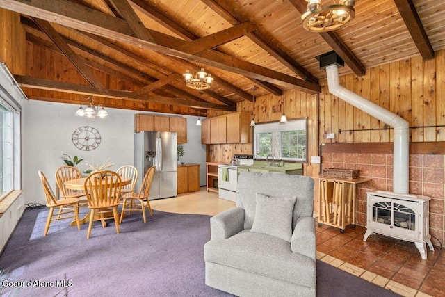 14314 N Waters Edge Ct, Hayden, ID 83835 - kitchen with stainless steel fridge with ice dispenser, white range with electric stovetop, a wood stove, a chandelier, and a wooden ceiling with exposed beams