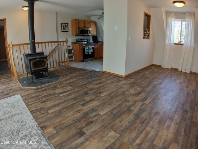 24731 N Wendler Loop, Rathdrum, ID 83858 - living room with dark wood finished floors, a wood stove, baseboards, and ceiling fan