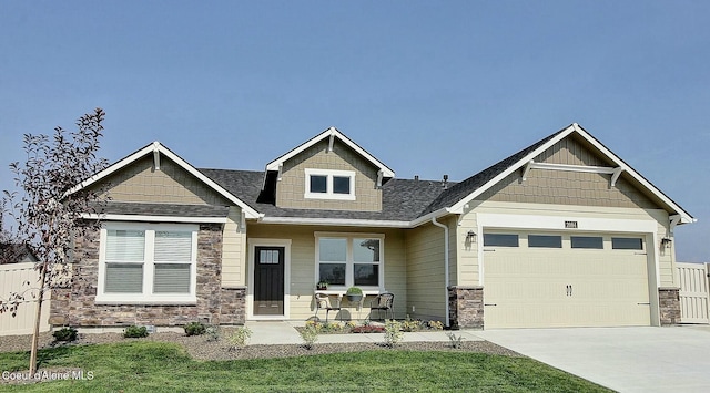 craftsman-style home with a front lawn, driveway, stone siding, an attached garage, and fence