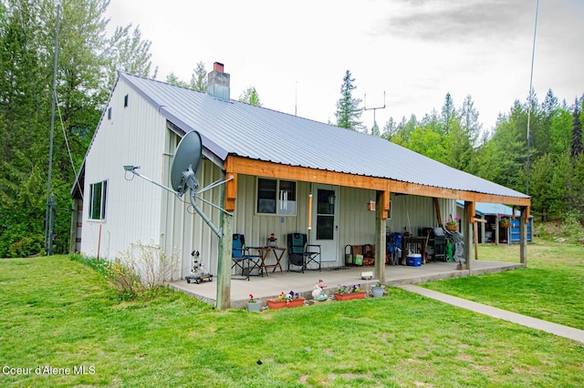 2884 Morris Rd, Naples, ID 83847 - rear view of house with a chimney, board and batten siding, a yard, a patio, and metal roof