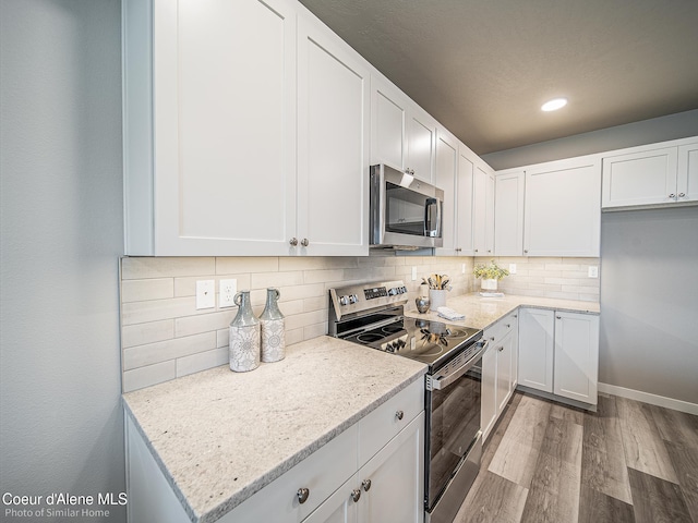 13748 N Apex Way, Hayden, ID 83835 - kitchen with appliances with stainless steel finishes, wood finished floors, light stone countertops, and white cabinetry