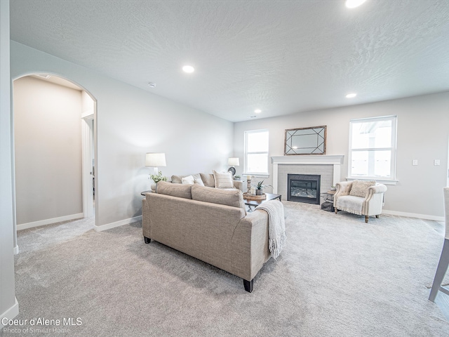 13748 N Apex Way, Hayden, ID 83835 - living room with a fireplace, carpet, a textured ceiling, and arched walkways