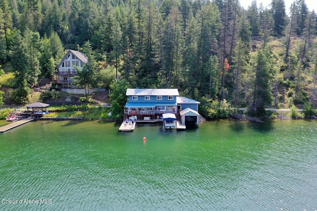 view from above of property featuring a heavily wooded area and a nearby body of water