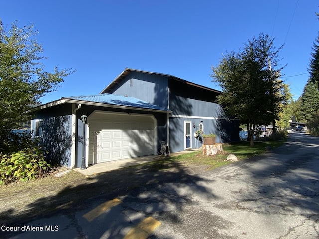 view of home's exterior with a garage, driveway, and metal roof