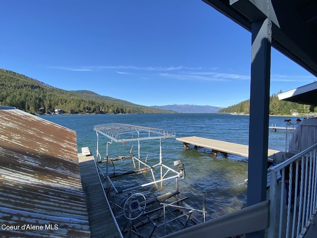 dock area featuring a water and mountain view and a wooded view