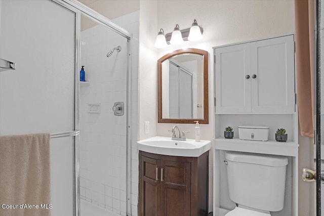 bathroom with toilet, vanity, and a shower stall