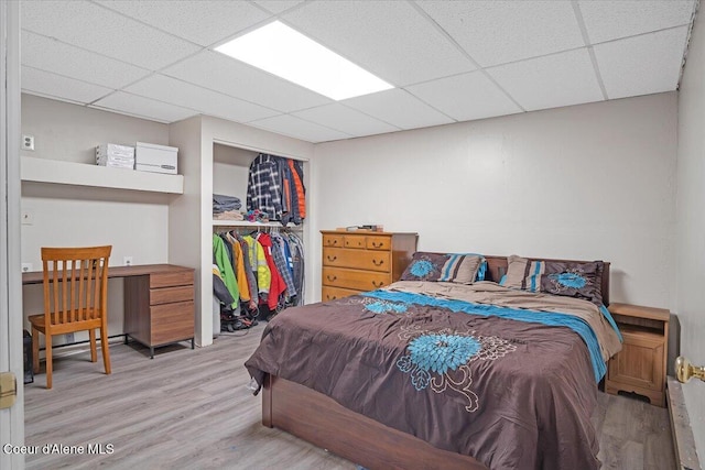 bedroom featuring wood finished floors, a paneled ceiling, and a closet
