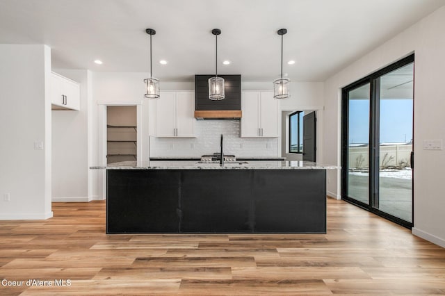 NNN Rocky Rd, Rathdrum, ID 83858 - kitchen with custom exhaust hood, a center island with sink, white cabinetry, and light wood-style flooring