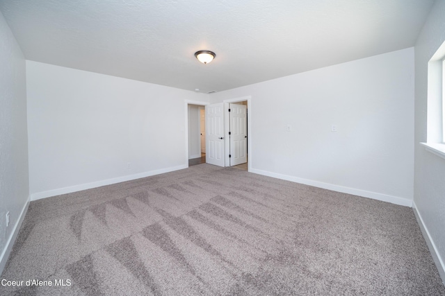 carpeted empty room with baseboards