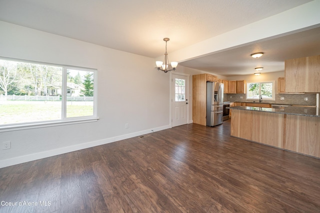 kitchen with dark wood-style flooring, baseboards, backsplash, stainless steel refrigerator with ice dispenser, and a notable chandelier